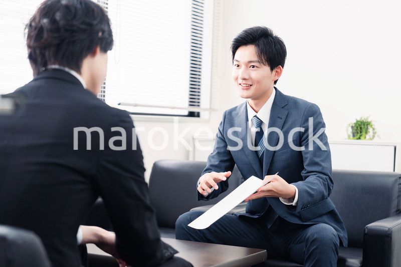 商談で書類を提示するビジネスマン