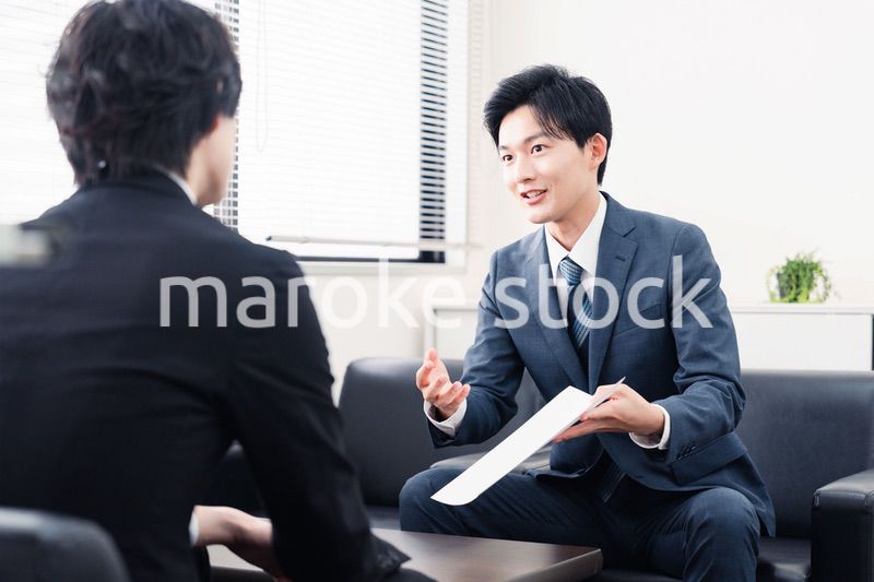 商談で書類を提示するビジネスマン