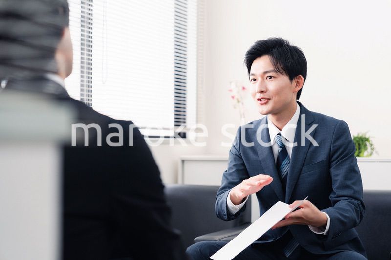 商談で書類を提示するビジネスマン