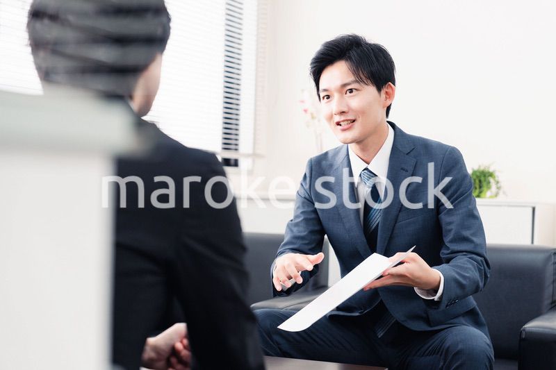 商談で書類を提示するビジネスマン