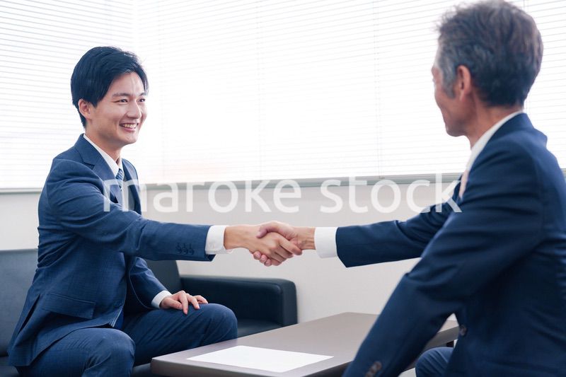 得意先と握手をするビジネスマン