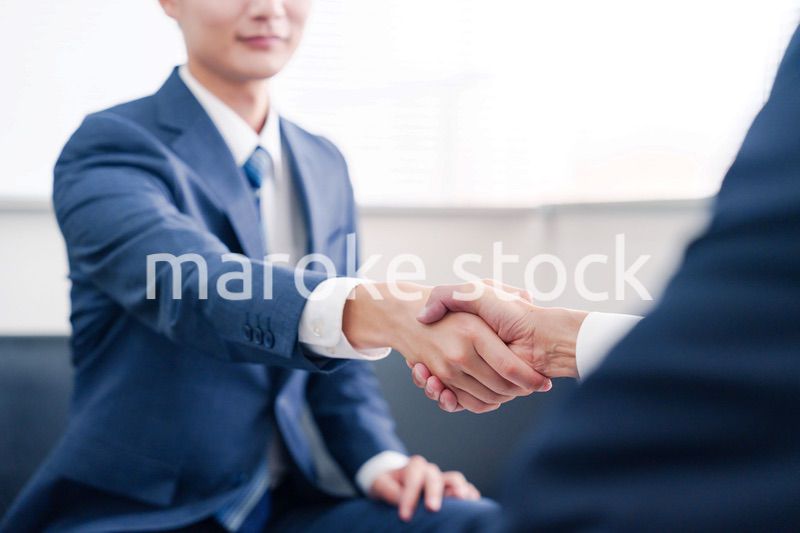 得意先と握手をするビジネスマン