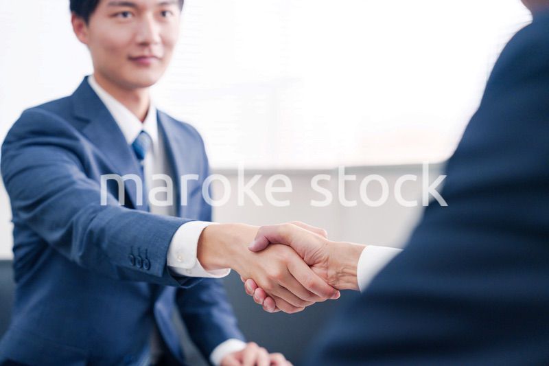 得意先と握手をするビジネスマン