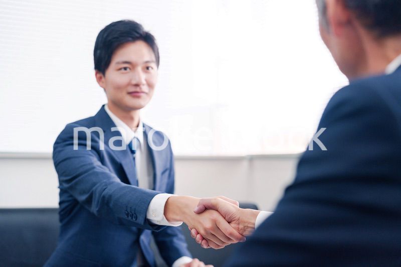 得意先と握手をするビジネスマン
