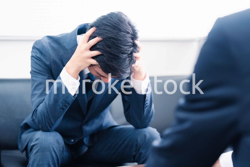 上司に呼び出されて頭を抱えるビジネスマン