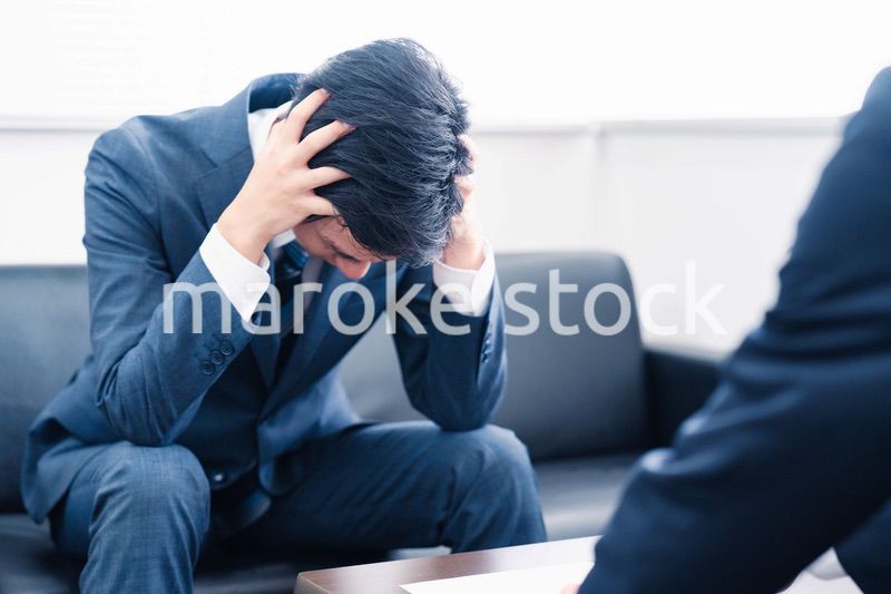 上司に呼び出されて頭を抱えるビジネスマン