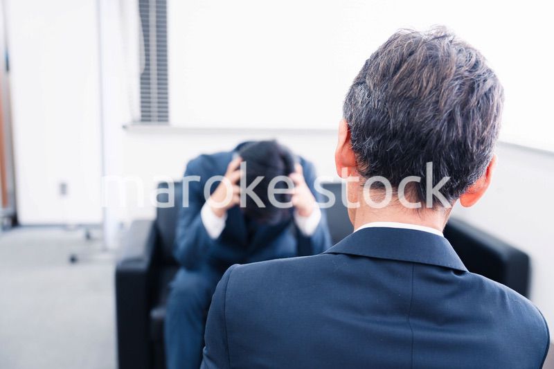 上司に呼び出されて頭を抱えるビジネスマン