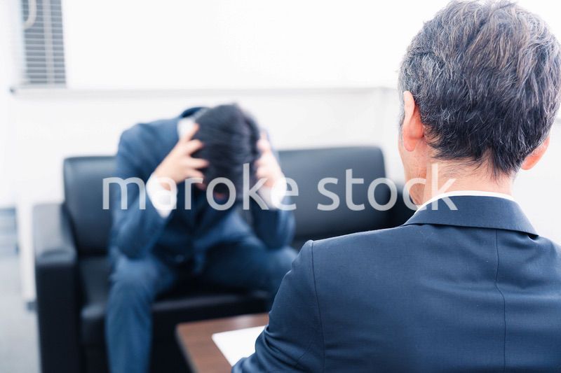 上司に呼び出されて頭を抱えるビジネスマン
