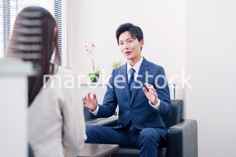 笑顔で得意先と商談をする営業マン