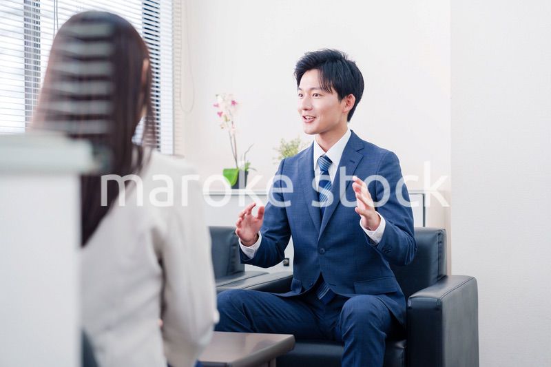 笑顔で得意先と商談をする営業マン