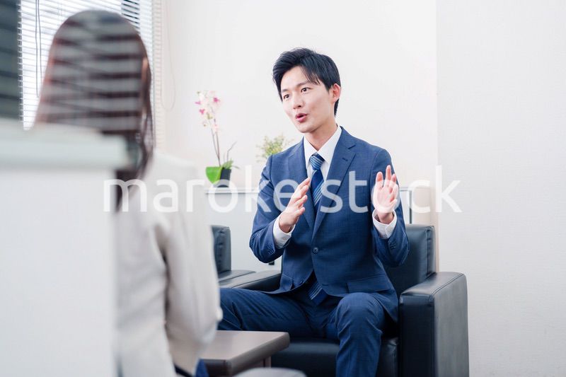 笑顔で得意先と商談をする営業マン