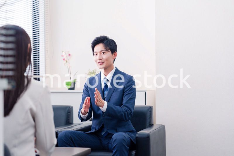 笑顔で得意先と商談をする営業マン