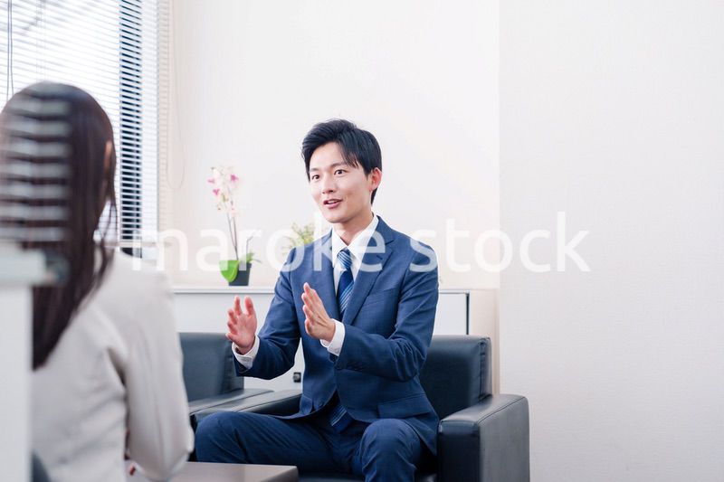 笑顔で得意先と商談をする営業マン