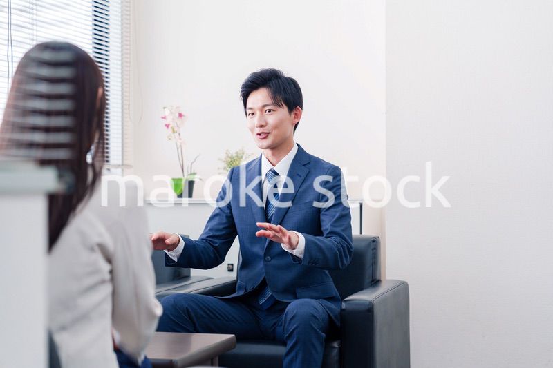 笑顔で得意先と商談をする営業マン