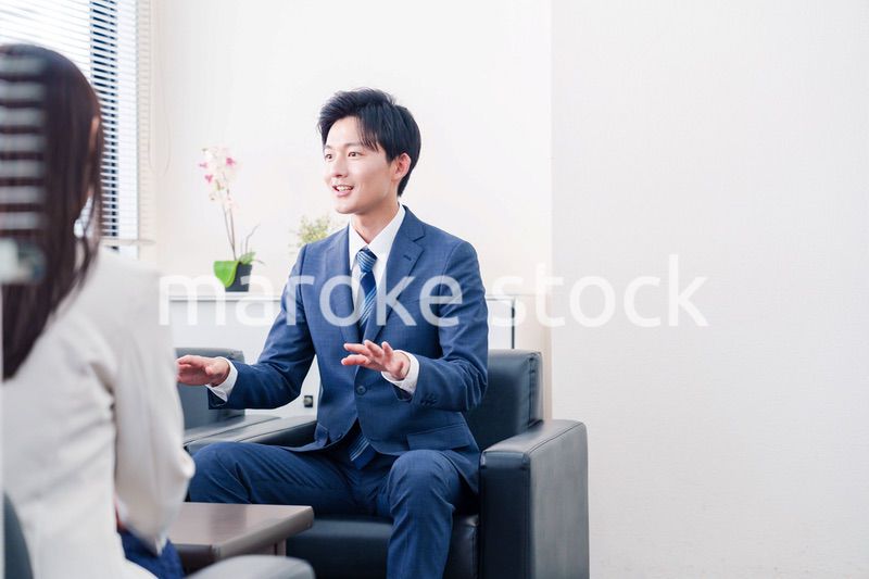 笑顔で得意先と商談をする営業マン