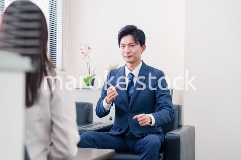 笑顔で得意先と商談をする営業マン