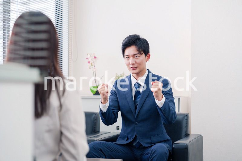 笑顔で得意先と商談をする営業マン