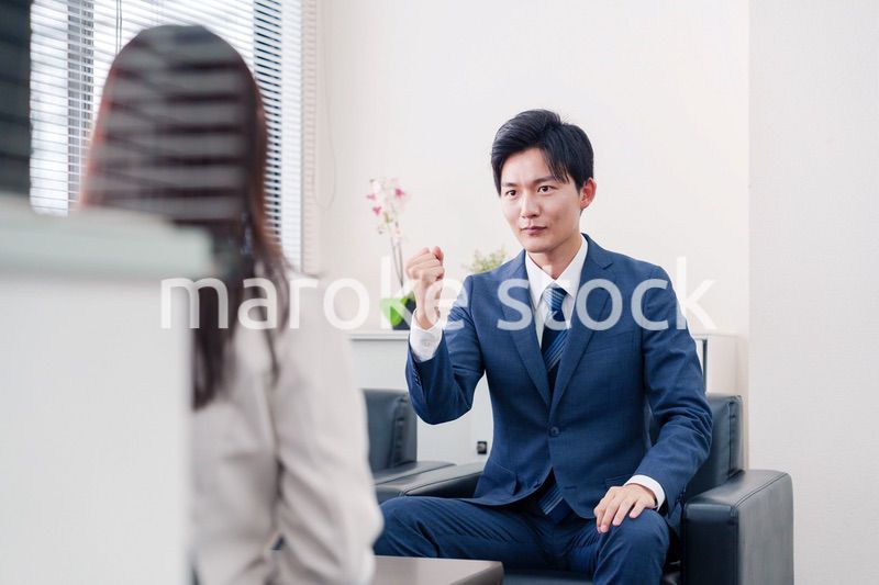 笑顔で得意先と商談をする営業マン