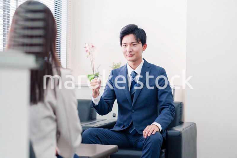 笑顔で得意先と商談をする営業マン