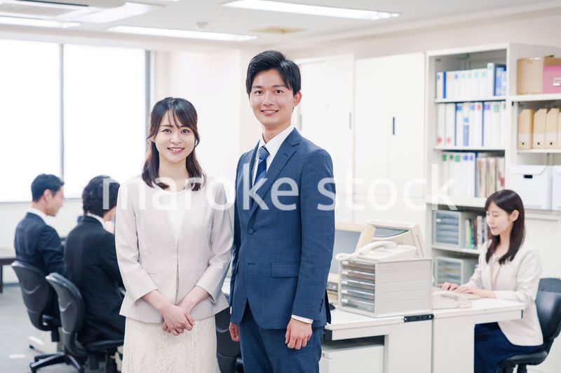 オフィスで笑顔でカメラ目線の男女のビジネスパーソン