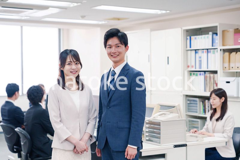 オフィスで笑顔でカメラ目線の男女のビジネスパーソン