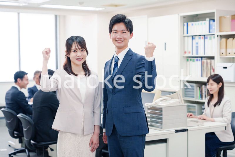 オフィスで笑顔でカメラ目線の男女のビジネスパーソン