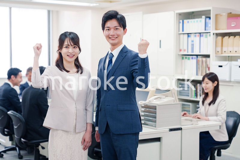 オフィスで笑顔でカメラ目線の男女のビジネスパーソン