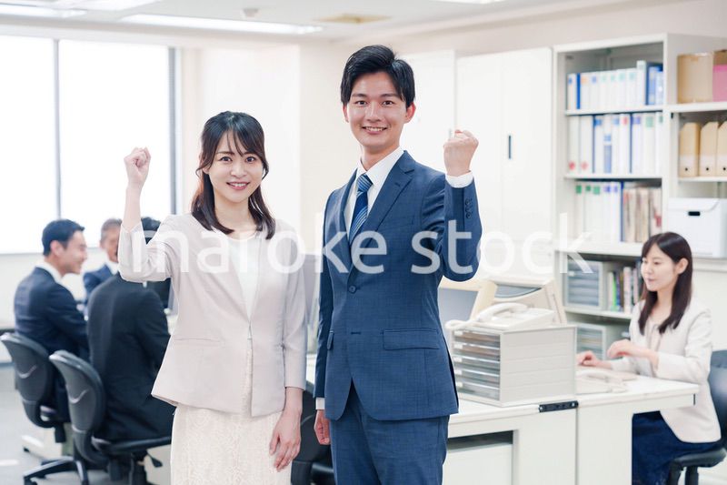 オフィスで笑顔でカメラ目線の男女のビジネスパーソン