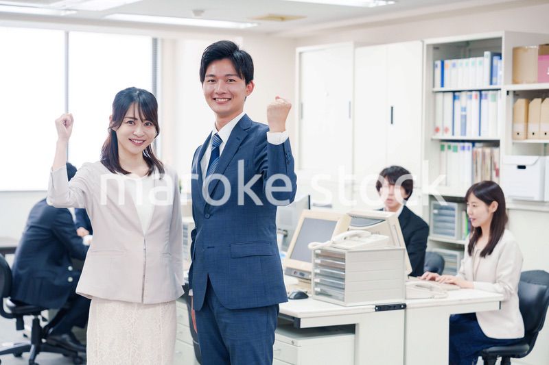 オフィスで笑顔でカメラ目線の男女のビジネスパーソン