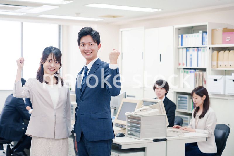 オフィスで笑顔でカメラ目線の男女のビジネスパーソン