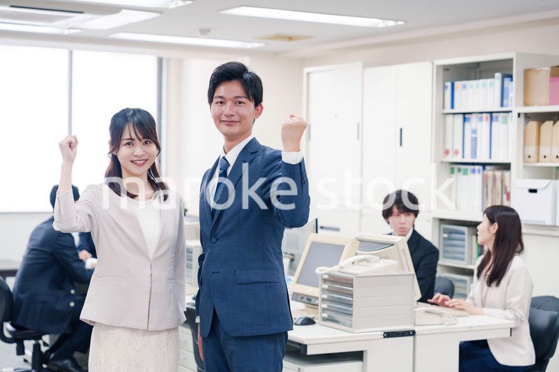 オフィスで笑顔でカメラ目線の男女のビジネスパーソン