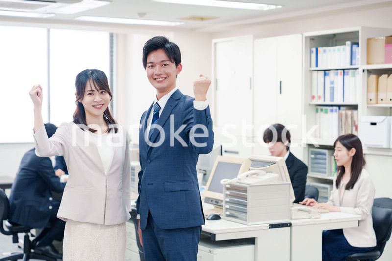 オフィスで笑顔でカメラ目線の男女のビジネスパーソン