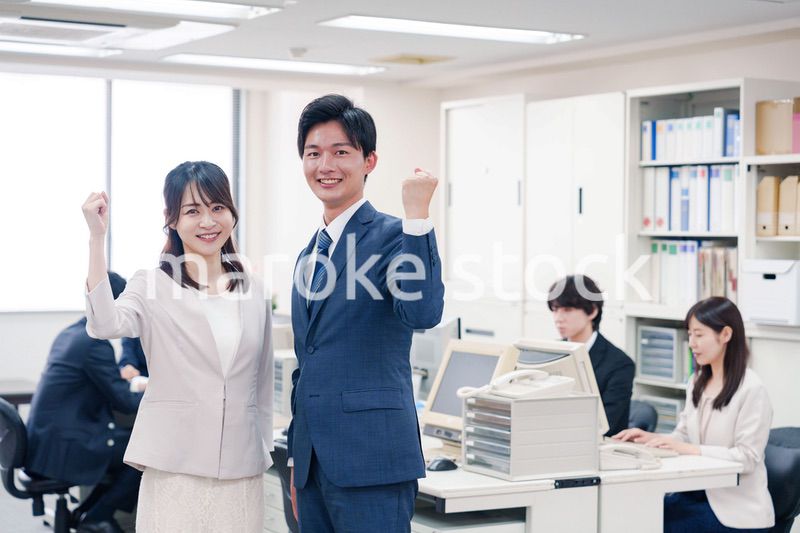 オフィスで笑顔でカメラ目線の男女のビジネスパーソン