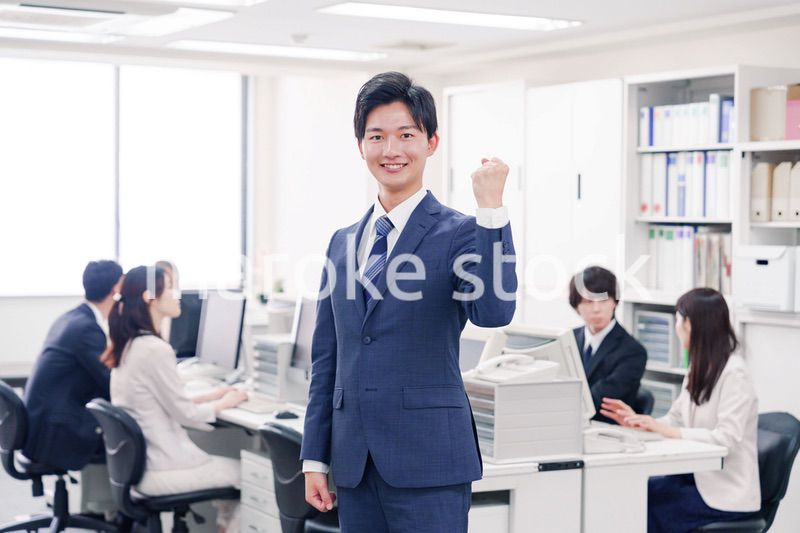 オフィスでガッツポーズをするスーツを着たビジネスマン