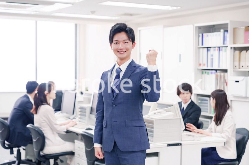 オフィスでガッツポーズをするスーツを着たビジネスマン