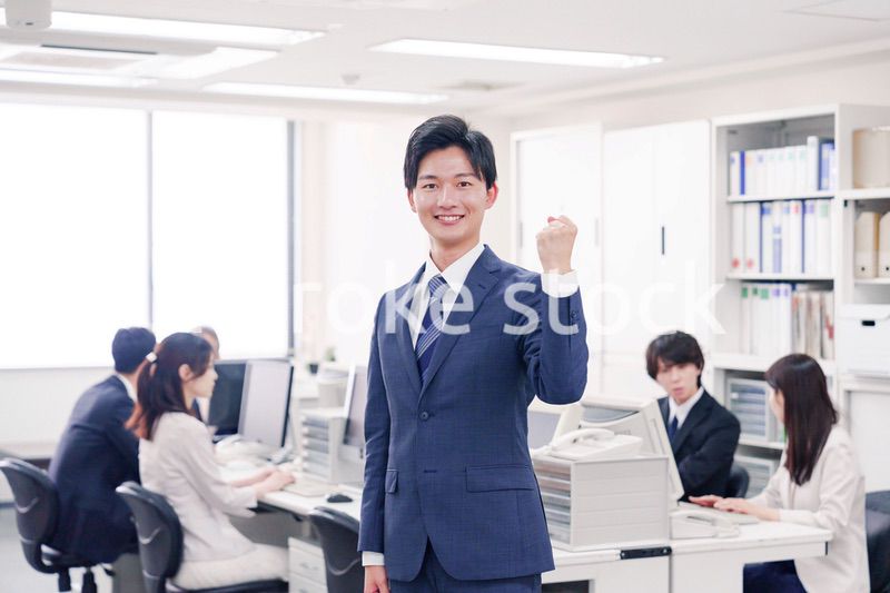 オフィスでガッツポーズをするスーツを着たビジネスマン