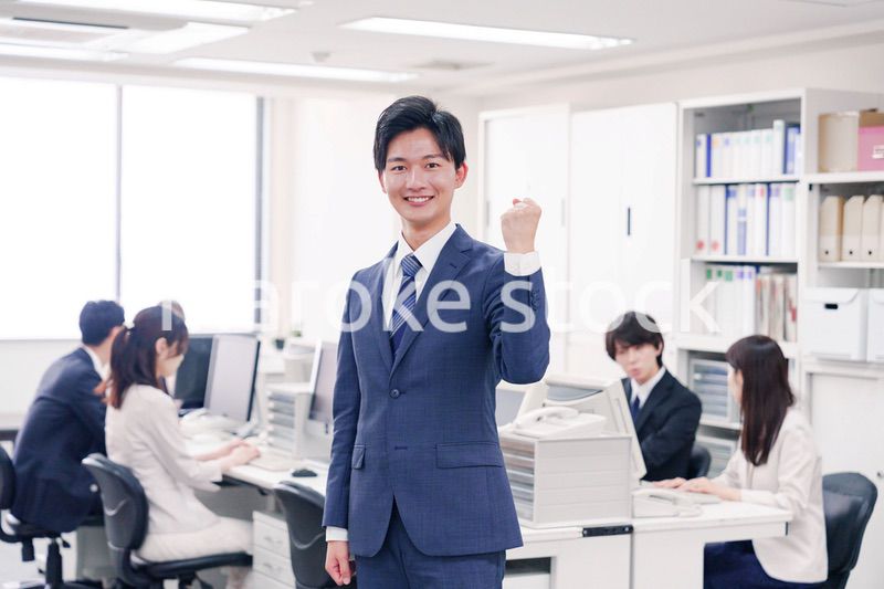 オフィスでガッツポーズをするスーツを着たビジネスマン