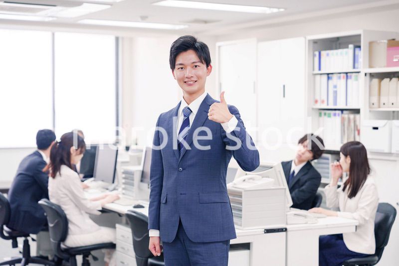 オフィスでグッドサインをするスーツを着たビジネスマン