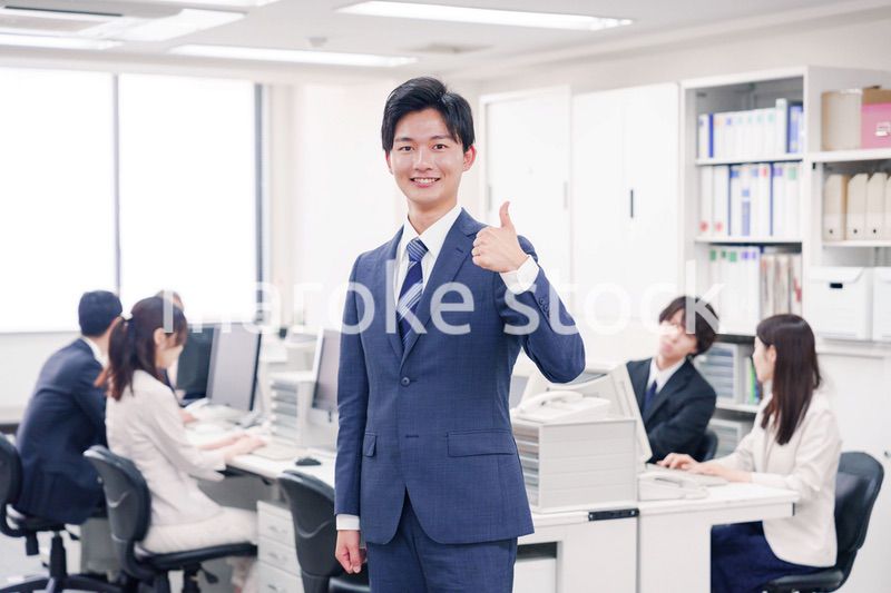 オフィスでグッドサインをするスーツを着たビジネスマン