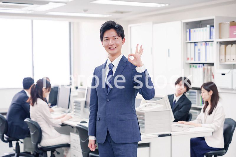 オフィスでグッドサインをするスーツを着たビジネスマン