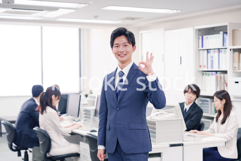 オフィスでグッドサインをするスーツを着たビジネスマン
