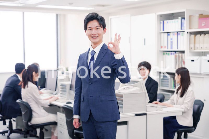 オフィスでグッドサインをするスーツを着たビジネスマン