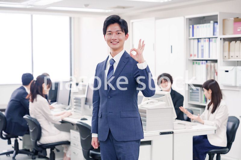 オフィスでグッドサインをするスーツを着たビジネスマン