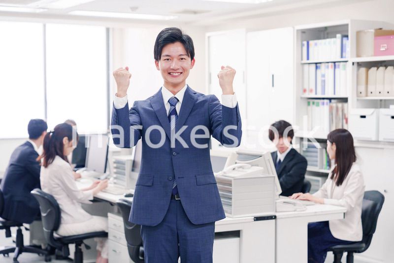 オフィスでグッドサインをするスーツを着たビジネスマン