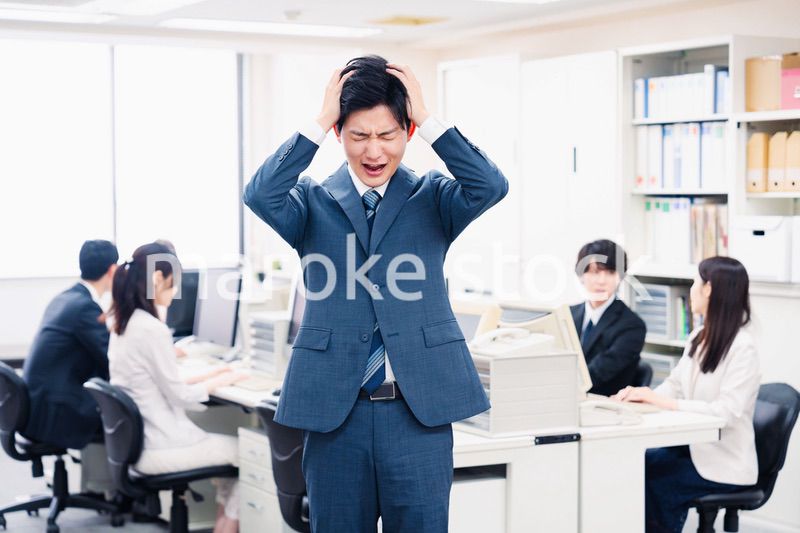 オフィスで頭を抱える若いビジネスマン