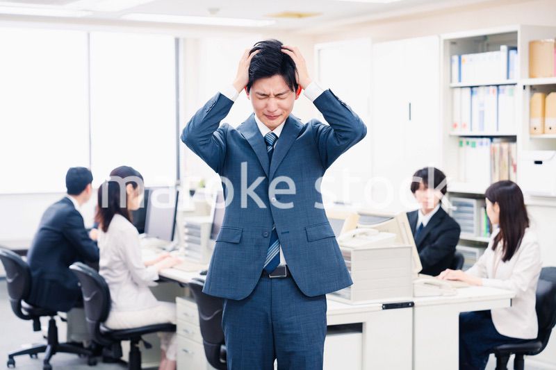 オフィスで頭を抱える若いビジネスマン