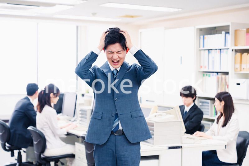 オフィスで頭を抱える若いビジネスマン