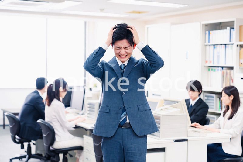 オフィスで頭を抱える若いビジネスマン