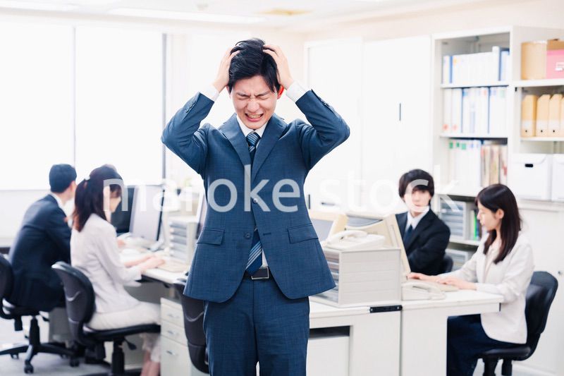 オフィスで頭を抱える若いビジネスマン