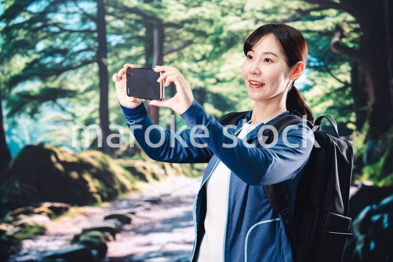 ハイキングをしながらスマホで写真を撮る若い女性